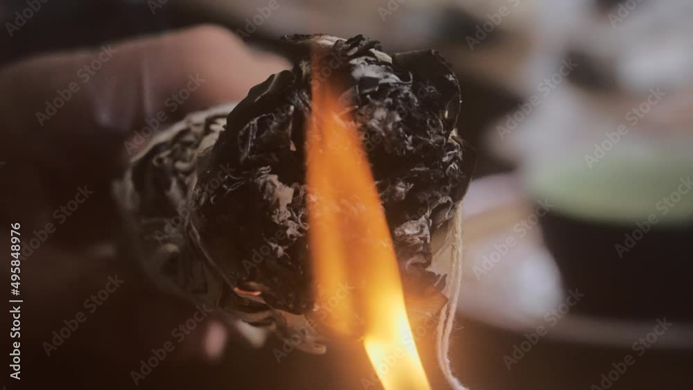 Closeup of fire lighting up a sage smudge stick - slow motion view