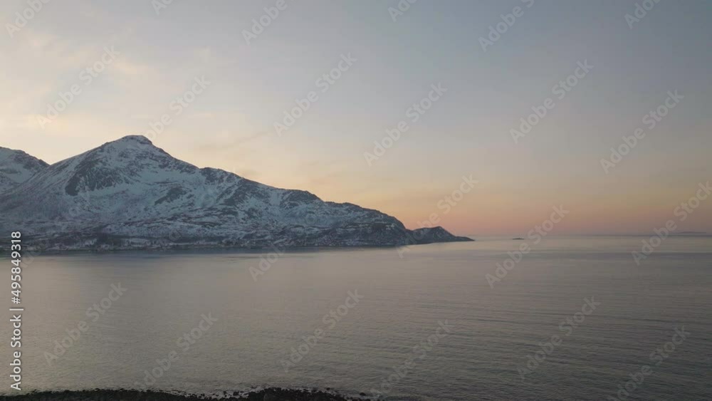 Golden hour aerial view over arctic waters, snow covered mountains in winter Golden hour aerial view over arctic waters, snow covered mountains in winter