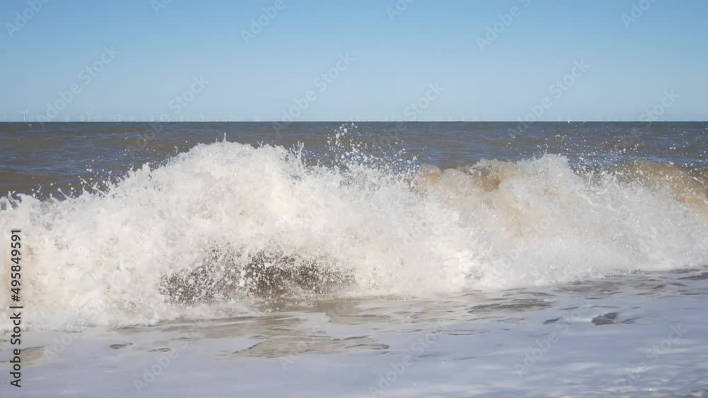 Powerful rolling waves crashing on to pebble beach shore spraying sea foam Powerful rolling waves crashing on to pebble beach shore spraying sea foam