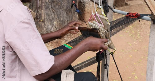 Handmade loom man making Kente cloth fabric close. Ghana, where the traditional cloth in Africa, Kente is made on hand looms, hand woven. The Kente is worn by the king of the Ashanti Kingdom. Complex. photo