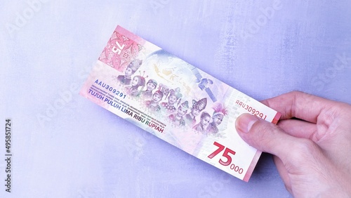IDR Indonesian Rupiah the official currency of Indonesia. Man's hand is making a payment. Business Loan Income Money Investment Economy and Finance Concept Uang 75000 75.000 Rupiah. Prosperity Concept