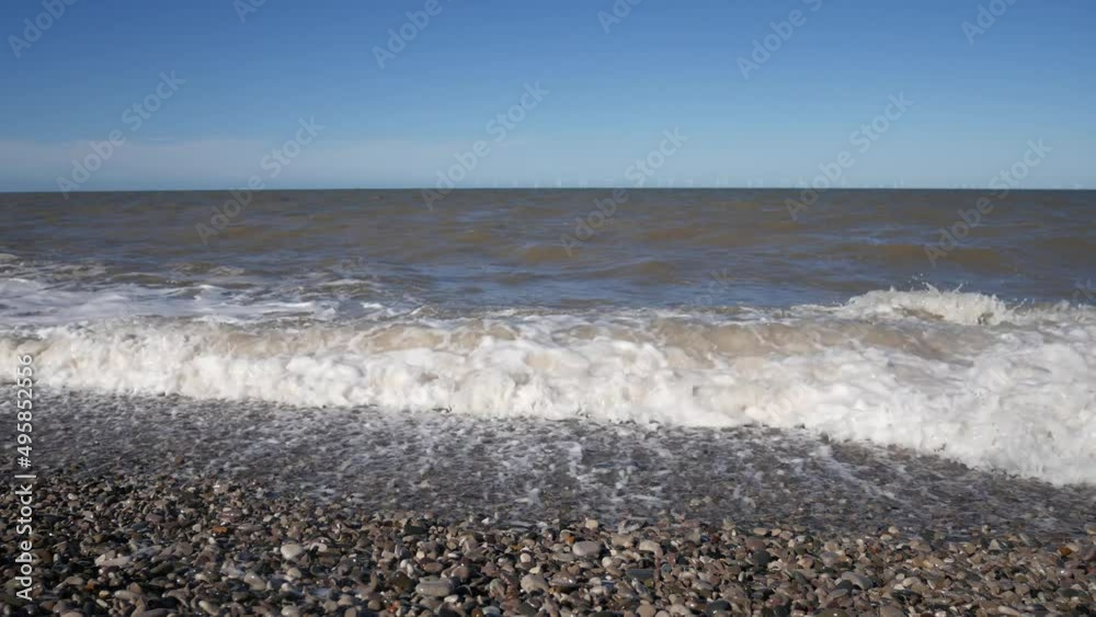 Relaxing repeating rolling waves crashing on to pebble beach shore spraying sea foam Relaxing repeating rolling waves crashing on to pebble beach shore spraying sea foam