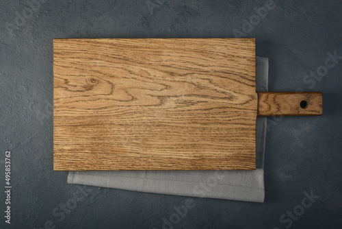 An old cutting board over a towel on a stone kitchen table.