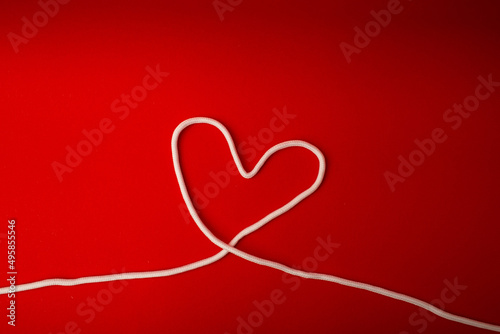 White shoe laces in the shape of a heart on a red background