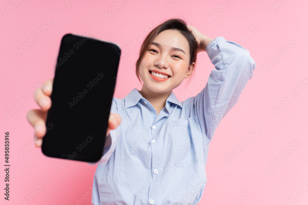 Image of young Asian girl holding smartphone on pink background Image of young Asian girl holding smartphone on pink background