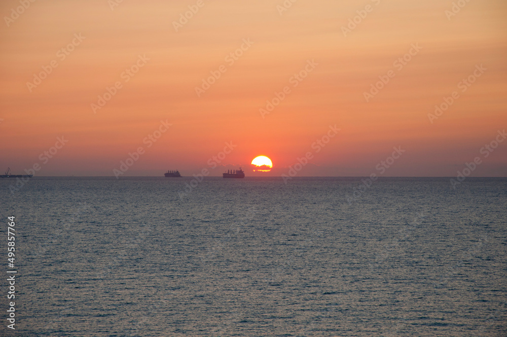sunset sky and sea with ship on horizon, summer vacation