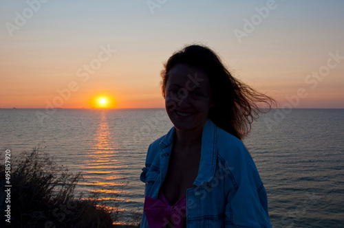 young woman smile look at summer sunset sun and sky with seascape