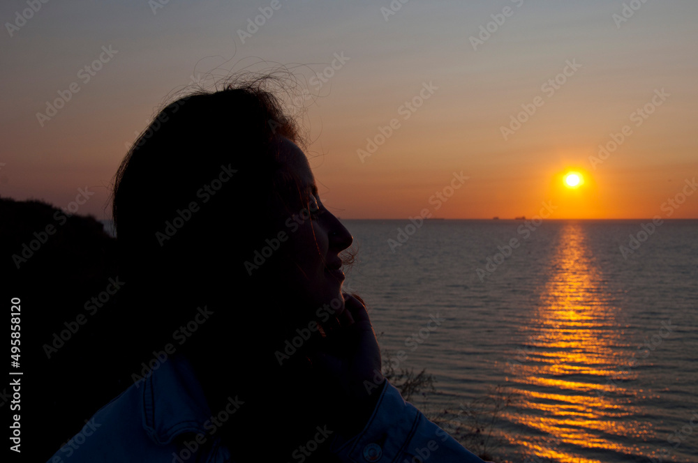 silhouette of girl look at summer dusk sun and sky with seascape. copy space