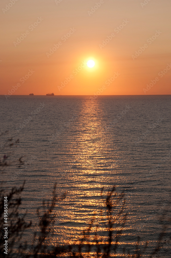 Naklejka premium sunrise sun and seascape with boat on horizon, summer