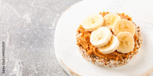 Crisp bread with peanut butter and bananas on a board. Selective focus. Copy space