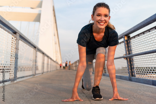 Young sport woman stretching and preparing to run outdoors in city