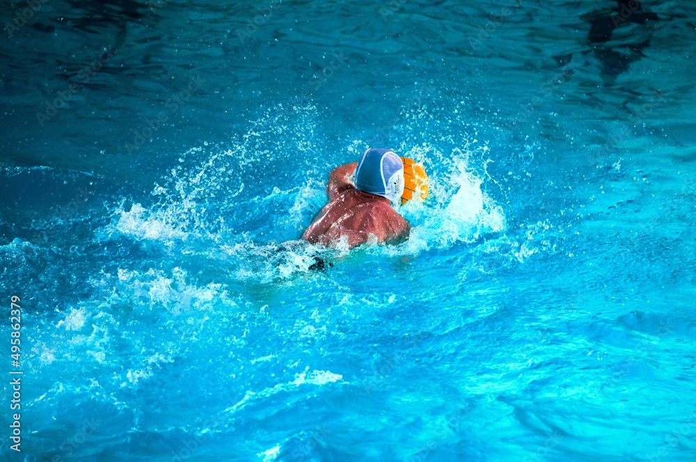 Young men play water polo in a swimming pool 