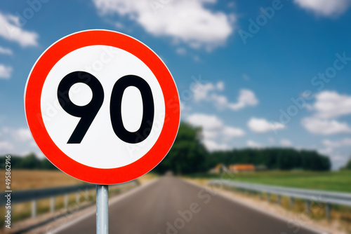 Speed limit sign with trees behind. Maximum ninety kilometers per hour. Safety on road background. White round sign red border line. Traffic ticket background. Speeding fine.