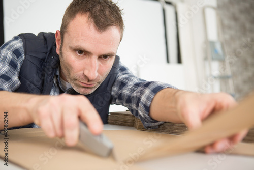 man using a craft knife to cut cardboard