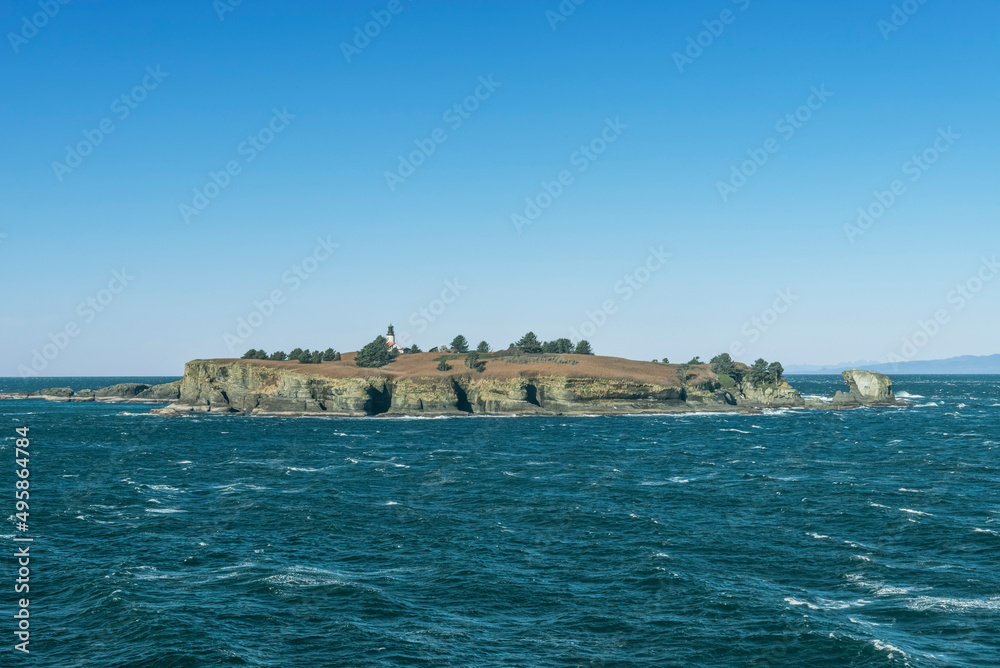 Lighthouse on an island in the sea off the Olympic Peninsula with Tatoosh mountains beyond. Lighthouse on an island in the sea off the Olympic Peninsula with Tatoosh mountains beyond.