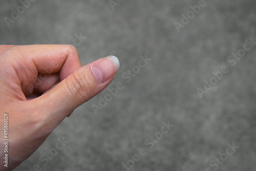 Closeup Unhealthy adult young woman’s fingernail with half moon shape and grey concrete ground as a background with copy space. Healthcare concept
