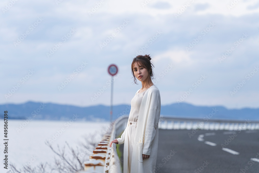夕暮れの海岸線を歩く女性