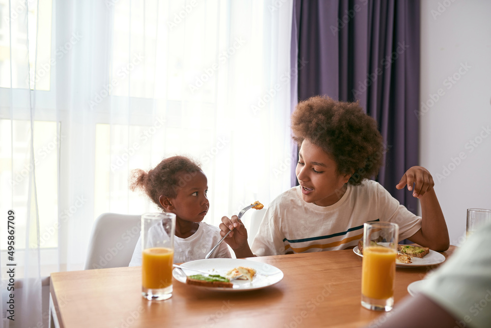 Boy showing sister how feeding himself with egg Boy showing sister how feeding himself with egg