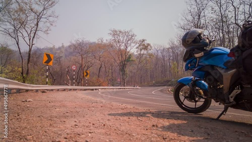 This timelapse captures the traffic at a hghway surrounded by light forests and the traveller's bike on the road in Uttarakhand, India.  photo