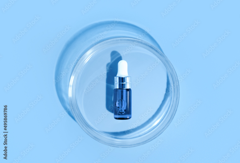 Blue bottle. Laboratory glass petri dish with pipette of water, serum, oil, beauty product. Natural medicine, cosmetic research, bio science. Skincare and analysis concept. Dermatology. Top view Blue bottle. Laboratory glass petri dish with pipette of water, serum, oil, beauty product. Natural medicine, cosmetic research, bio science. Skincare and analysis concept. Dermatology. Top view