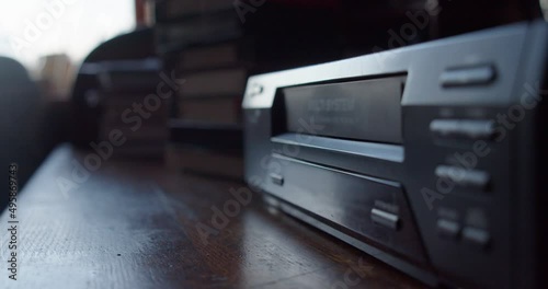 video cassette climbs out of analog video recorder, hand pulls it out