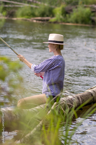 Young woman fishing at lake in summer
