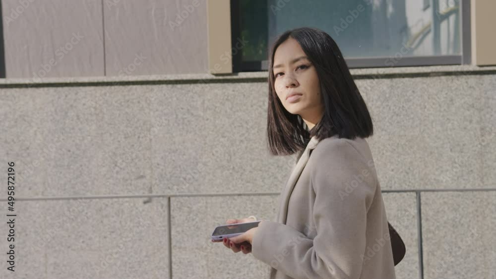 Side view of an adult asian businesswoman walking in the city Side view of an adult asian businesswoman walking in the city