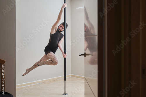 Young man wearing make up and fishnet stockings pole dancing. Gender identity.