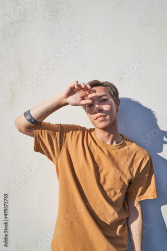 Fotografering Man in front of wall with hand in front of face