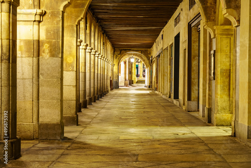 Arcades with columns and arches of the main square of Salamanca at night.