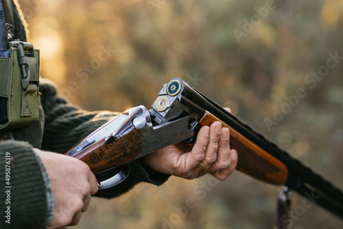 Man loading cartridges in gun for hunting in forest photo