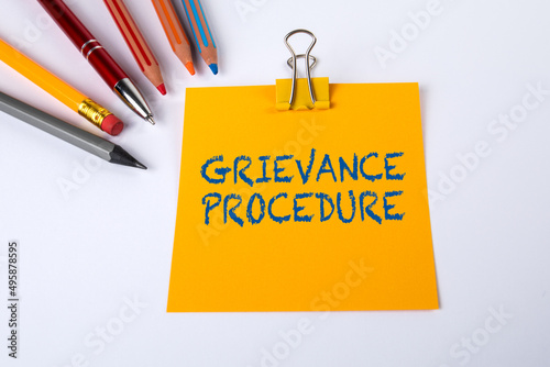Text GRIEVANCE PROCEDURE on yellow piece of paper. White office desk photo