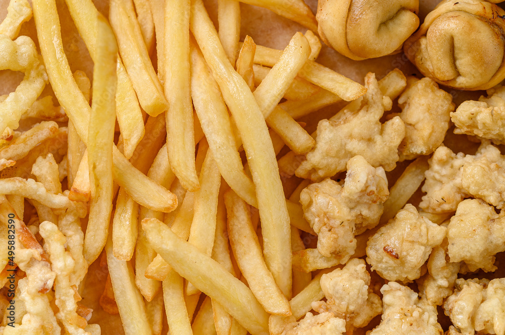 Close-up fragment of a multiple french fries potato chips and fried pies as a food backdrop composition Close-up fragment of a multiple french fries potato chips and fried pies as a food backdrop composition