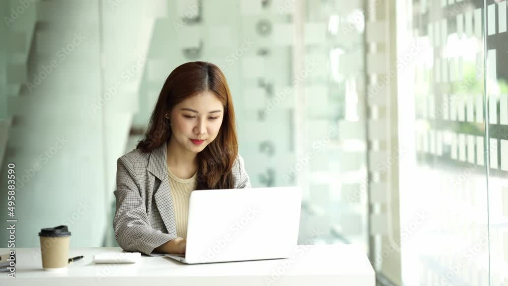 Charming asian businesswoman sitting working on laptop in office. Charming asian businesswoman sitting working on laptop in office.