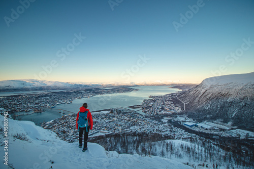 Foto Female Adventurer in a red jacket and backpack stands atop a fjellheisen and wat
