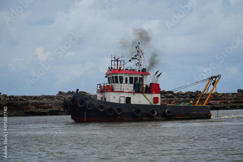 Old tug boat with black exhaust plume in the harbor of the Brazilian port city of Recife, state of Pernambuco, Brazil. photo