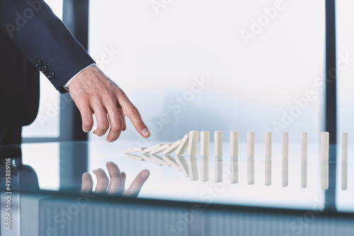 businessman pushing dominoes standing in a row.
