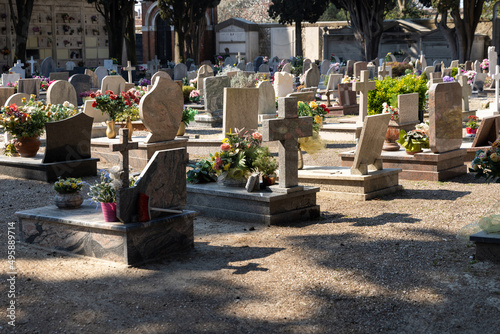 Italian cemetery with tombstones and artificial flowers on a sunny summer day in Venice, Italy, Island of San Michele. Commemoration of the dead, deaths of pandemic. photo