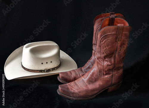 Cowboyhut und Westernstiefel freigestellt vor schwarzem Hintergrund photo