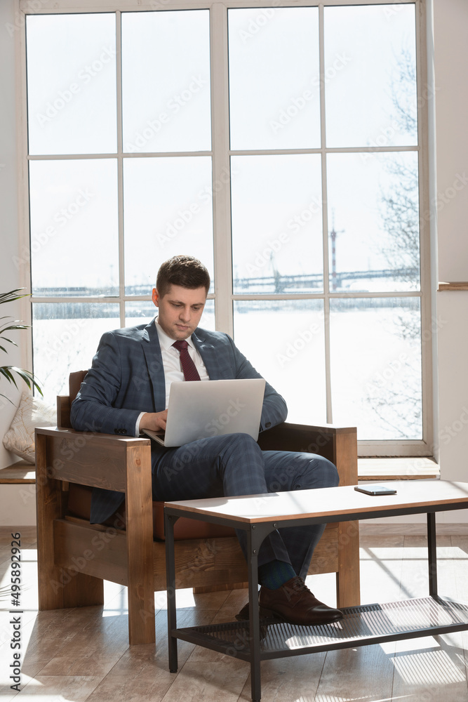 male freelancer using laptop while sitting at table and working from home. male freelancer using laptop while sitting at table and working from home.