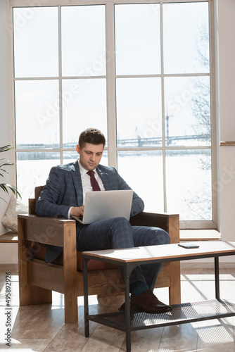 male freelancer using laptop while sitting at table and working from home.