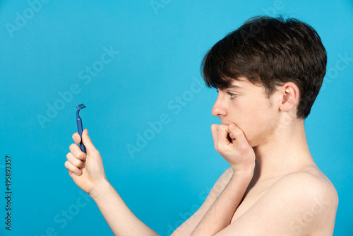 Side view of teenager boy looking to razor with fear. photo