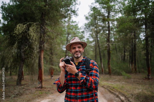 Portrait of a man in a hat using the camera in the forest.