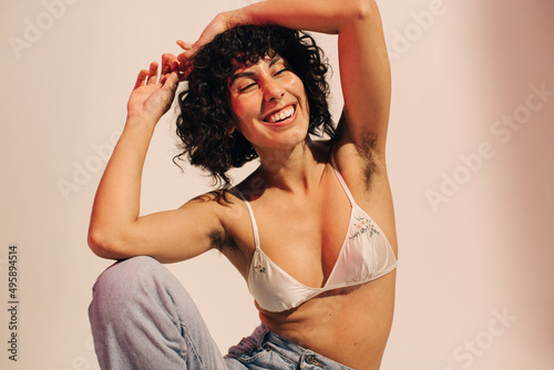 Unshaven young woman smiling cheerfully while wearing a bra photo
