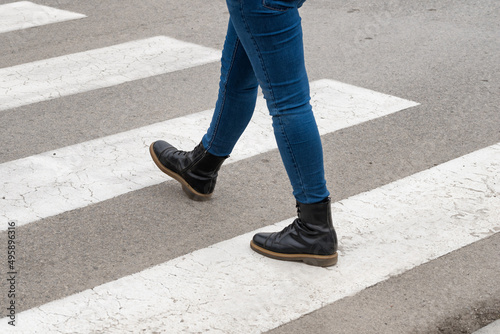 Pedestrians crossing. Woman legs in boots crossing the zebra crossing