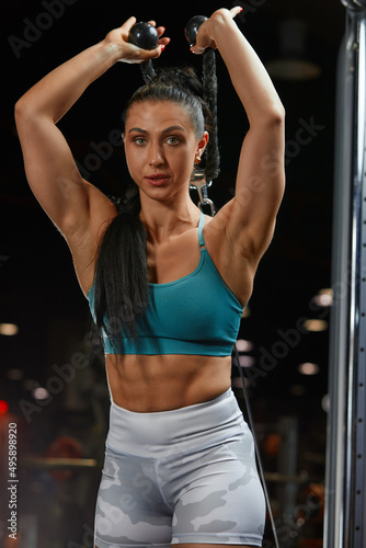 strong-willed young woman fitness coach engaged with a barbell in the simulator in the gym. Concept of strong muscles and taut figure