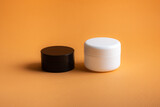 White and black package for body cream on orange background