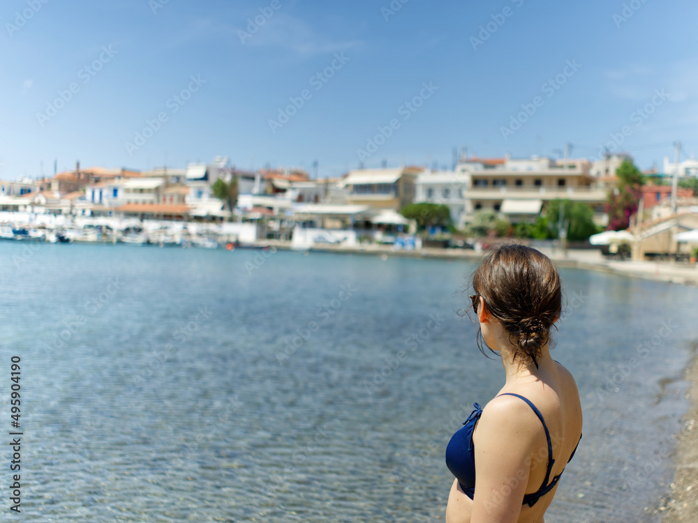beautiful young woman in a bathing suit enjoys the summer holiday on the beach with yachts in the background. close up