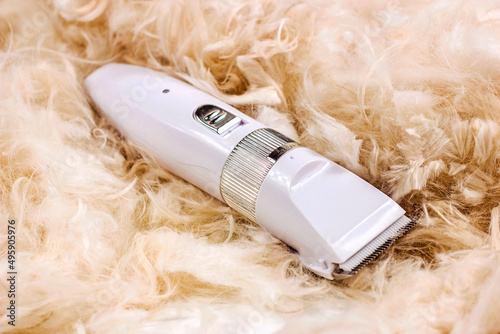 White pet hair trimmer of clipper machine for cat and dog grooming on light cutting fur background.