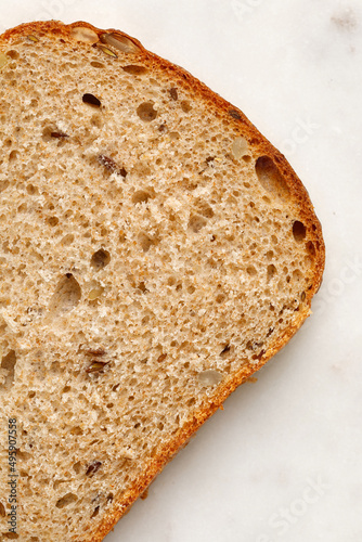 Slice of a whole wheat bread on a marble tray. Healthy Hand Made Bread. Macro, close up, texture of bread